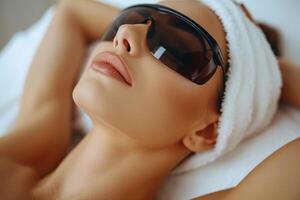 Close up portrait of a young woman patient receiving a laser treatment in a spa salon. photo