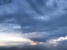 a dark sky with clouds and a bird flying in the sky photo