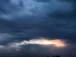 a dark sky with clouds and a bird flying in the sky photo