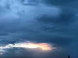 a dark sky with clouds and a bird flying in the sky photo