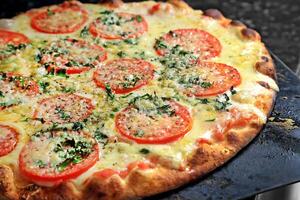 Margherita pizza coming out of the oven with cheese, tomato sauce and basil photo