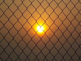 Sunset view behind chain-link fences photo