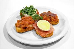 bruschettas with parma ham, tomatoes, buffalo mozzarella and aliche on toasted bread photo