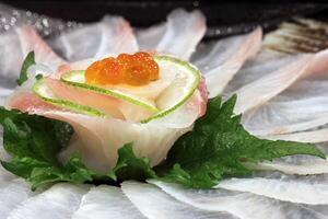 Ussuzukuri, thin cuts of white fish immersed in ponzu sauce and sriracha pepper. photo