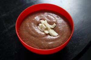 chocolate mousse in red plastic bowl with cocoa fruit slices photo