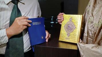 holding the bible of the new testament and the book of the quran photo