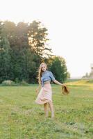 atmosférico retrato de un joven mujer en verano ropa caminando en naturaleza en contra el antecedentes de bosque arboles el concepto de juventud, libertad y verano Días festivos foto