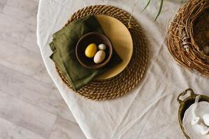 Table with a green napkin and a yellow plate with easter eggs and a bowl photo