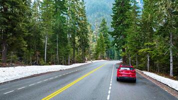 Beautiful natural wild landscape crossed by the speed highway. Car move by the roads in the mountainous area covered with pine tree forest. Aerial view. photo