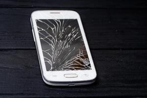 Phone with broken screen. Digital white smartphone with smashed screen. photo