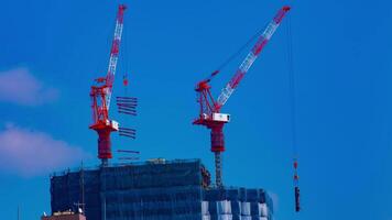 un lapso de tiempo de grúas a el debajo construcción detrás el azul cielo en tokio video