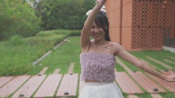 Asian girl dancing and cheering, moving her arms Inside the park during the day video