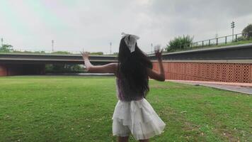 asiático niña bailando y aplausos, Moviente su brazos dentro el parque durante el día video