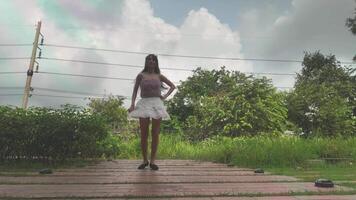 asiático niña bailando y aplausos, Moviente su brazos dentro el parque durante el día video