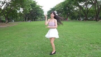 Asian girl dancing and cheering, moving her arms Inside the park during the day video