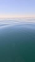 verticale aereo Visualizza su mare acqua superficie, telecamera mosche al di sopra di chiaro mare acqua. sole bagliore. astratto nautico estate oceano natura. vacanza, vacanza e viaggio concetto. nessuno. tempo metereologico e clima modificare video