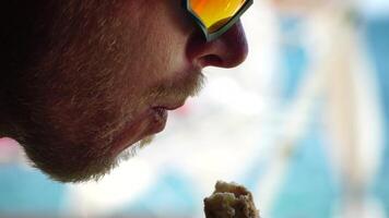 Man eating ice cream. Close-up portrait of young hipster man in sunglasses eating ice cream in summer hot weather on the beach, have fun and good mood. Travel, tourism, vacation, pleasure, enjoying. video