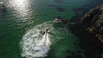 en man flugor på en flyboard. antenn topp ner se. vatten extrem sport, azurblå sommar hav med utomhus aktiva människor njuter vatten sporter. flyboard och searing, rekreation och sporter begrepp. video