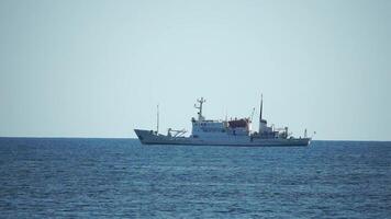 Fishing boat trawler catches fish while sailing on sea. A commercial fishing boat on the horizon in a distance sail to catch school of fish on calm sea surface in summer. Commercial catch of sea fish. video