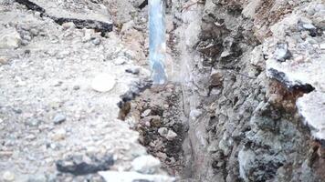 destrucción de sólido suelo rock con neumático martillo neumático excavador. cerca arriba de un excavador excavación un profundo zanja. un excavador alojamiento un zanja en el campo a laico un agua tubo. video