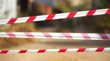 Red and white warning tape swinging in the wind. Protection sign. Don't cross the line. Red White caution tape pole fencing is protects for No entry. Backdrop without people, empty street. video