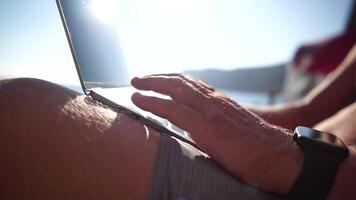 homem computador portátil mar. trabalhando remotamente em Beira Mar. feliz bem sucedido homem masculino trabalhador autonomo trabalhando em computador portátil de a mar às pôr do sol, faz uma o negócio transação on-line. freelance, controlo remoto trabalhos em período de férias video