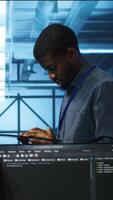 Vertical Manager uses tablet, supervising team programming servers providing computing resources for different workloads. Inspector using device to oversee engineers in data center mending supercomputers video