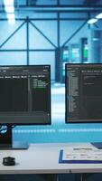 Vertical Lines of code running on computer screens in data center, used for troubleshooting rackmounts in server rows. Close up shot of script working on PC monitors upgrading hardware video