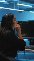 Vertical Team of IT support experts working together, supervising server rows in computer network security data center. Woman next to colleagues talking in headphones mic while overseeing supercomputers video