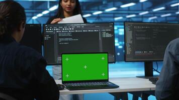 Manager in server hub supervising engineers looking for misconfiguration using isolated screen device. Woman coordinating experts mending data center bugs with mockup notebook, close up panning shot video