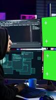 vertikal hacker utvecklande spyware programvara på grön skärm dator till stjäla Viktig data till vara såld på svart marknadsföra. huvor bedragare skrivning illvillig koda på krom nyckel pc, kamera b video