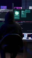 Vertical Lone wolf hacker in secret hideout trying to hide online activity after stealing data. Cybercriminal attacking victims PCs using computer virus, trying to avoid being detected, camera B video