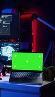 Vertical Green screen laptop used by hacker in underground hideout to write lines of code, developing virus that get past security systems. Chroma key device used by evil developer in hidden bunker, camera B video