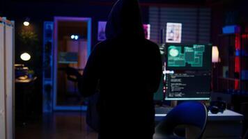 Hacker arriving in hidden underground shelter, prepared to launch DDoS attack on websites. Cybercriminal in apartment starting work on script that can crash businesses servers, camera B video