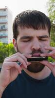 Jeune homme pièces la musique avec bouche harmonica en plein air video