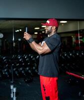 Muscular strong male resting in the gym. Attractive handsome man in cap smilling in gym. photo