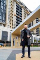 Handsome stylish man standing on modern city street. Attractive confident male in casual trendy cloth. photo