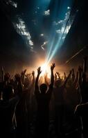 Silhouette of crowd of people dancing at concert with raised up hands and bright lights photo