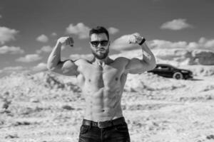 Muscular bare torso. Man with muscular body posing outdoors shirtless. photo