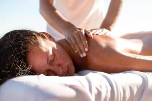 Masseur massaging the back of relaxed woman on sunny day photo