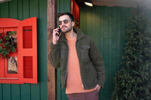Handsome man talking on smartphone near Christmas tree photo
