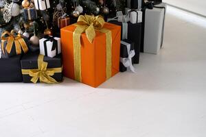 Christmas present box black, orange and white color on white floor with copy space photo