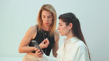 femmina cliente mostrando smartphone per trucco artista nel studio video