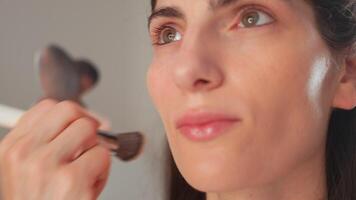 Makeup artist applying foundation on woman's face in studio video