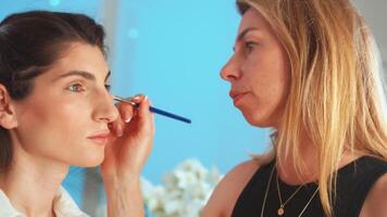 femmina trucco artista l'applicazione evidenziatore su donna di viso nel studio video