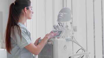 hembra cosmetóloga utilizando moderno hidrofacial máquina en moderno clínica video