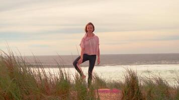 Fit woman doing tree yoga pose on seashore video