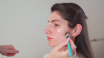 trucco dell'artista mano l'applicazione fondazione su del cliente viso nel studio video