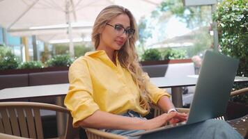 Woman developer coding on laptop at outdoor restaurant video