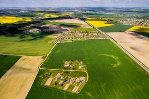 top view of a sown green field and a small village in Belarus. Agricultural fields in the village.Spring sowing in a small village photo